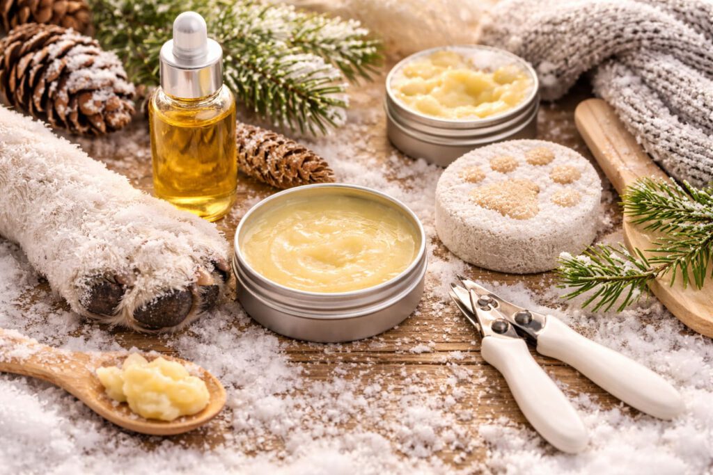 pfotenbalsam hund selbermachen, Hundepfote mit Pfotenbalsam und Krallenschere in winterlicher Atmosphäre